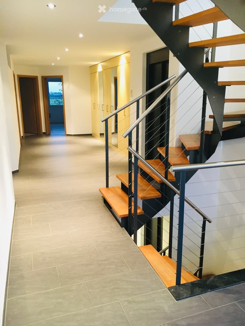 modern staircase with wooden steps and metal railings, tiled floor, white walls, two doors, one leading to an elevator