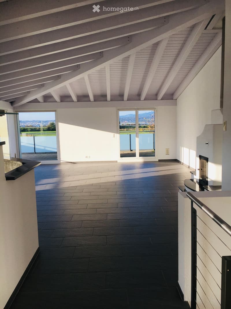Open space with large windows, black tiled floor, white walls, fireplace, balcony