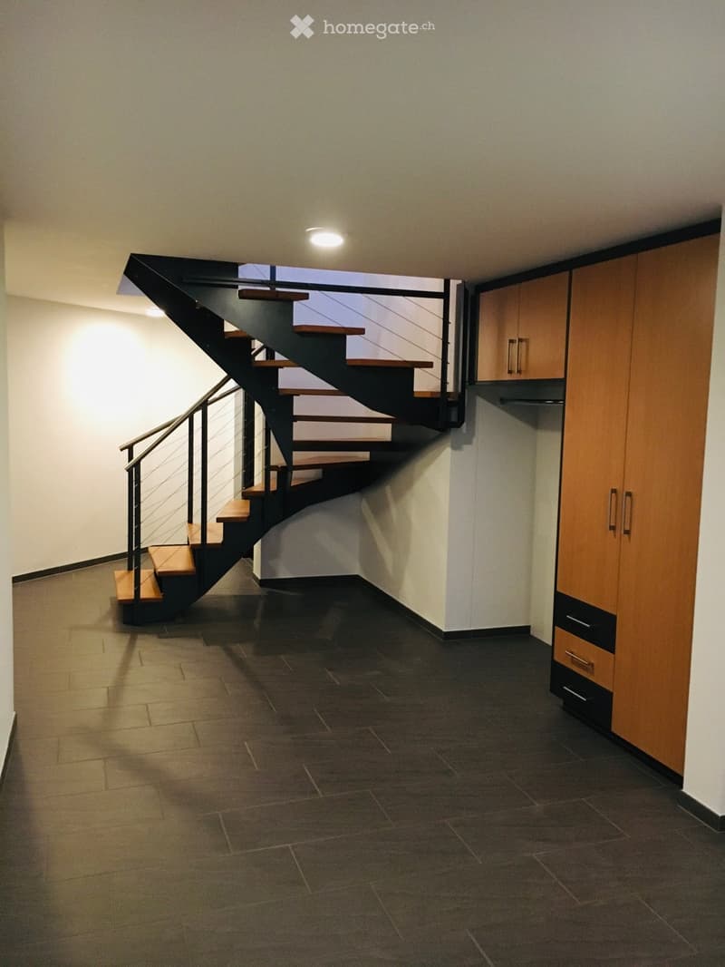 empty room, black tiled floor, white walls, spiral staircase, wooden cabinets, metal handrail