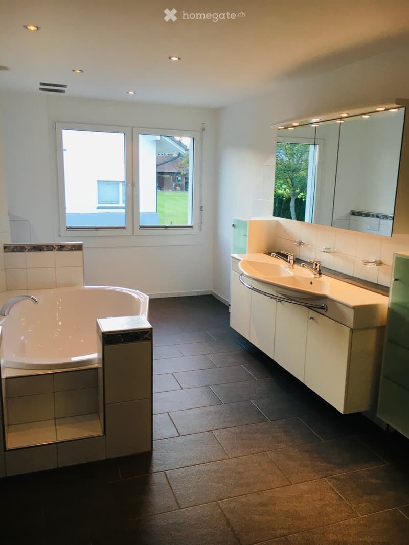 Bathroom with bathtub, double sink, and large mirror