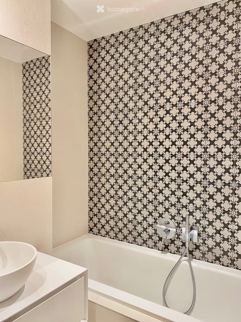 Bathroom with white bathtub, white sink, white cabinet, patterned wall tiles