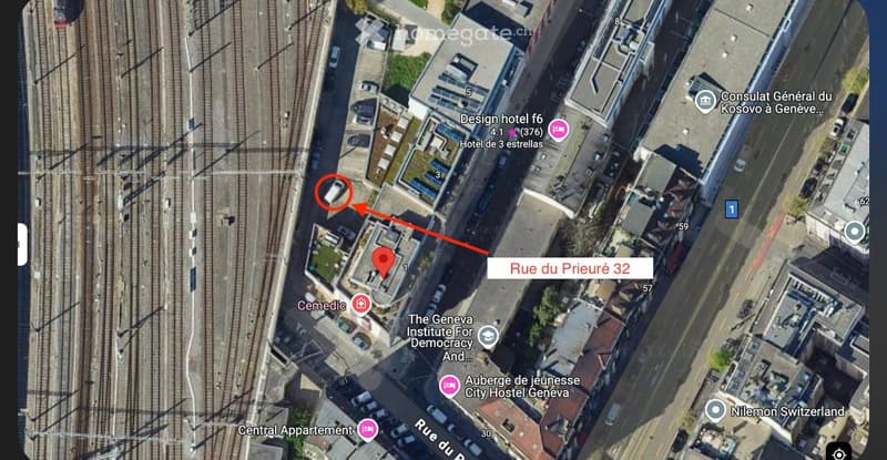 Aerial view of a city with buildings, roads, and railways. The map shows Rue du Prieuré 32, a building with a red arrow pointing to it.