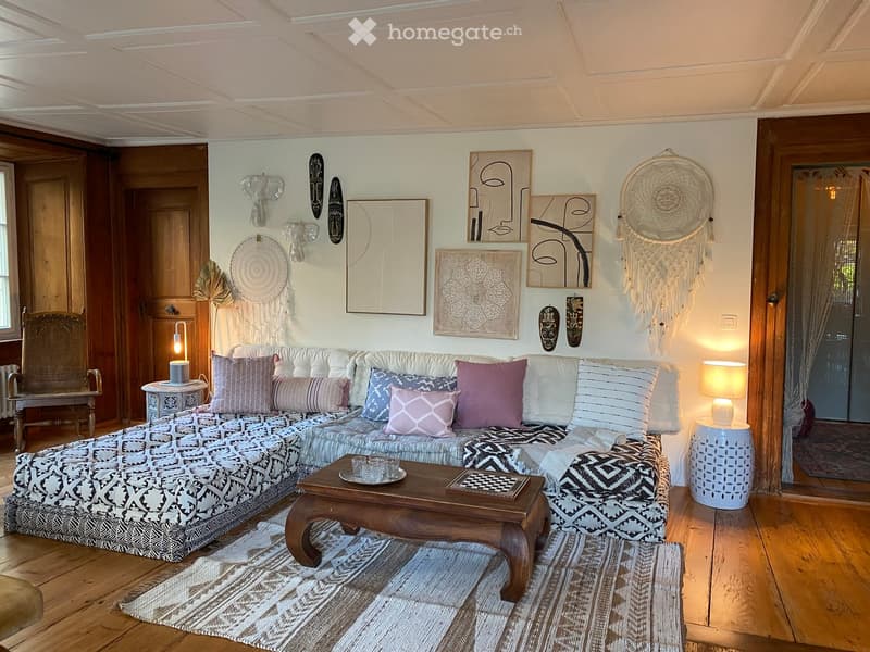 L-shaped sofa, wooden coffee table, chess board, side tables, lamps, rug, wooden floor, wooden doors, wall art