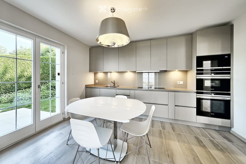 modern kitchen with white table and chairs, gray cabinets, double oven, sink, large windows