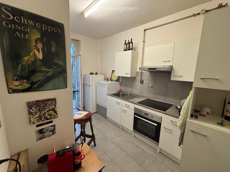 modern kitchen with white cabinets, tiled floor, gas stove, sink, refrigerator, and a poster on the wall