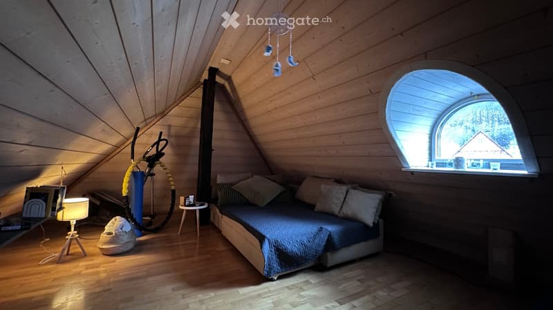 wooden walls, bed with pillows, lamp, small table, arch window, dream catcher