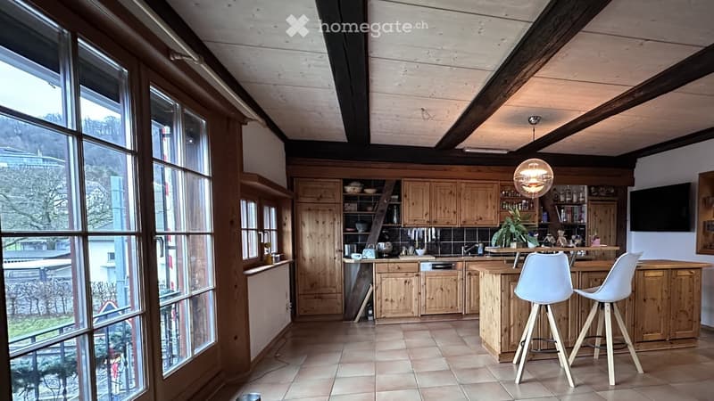 kitchen with large windows, wooden cabinets, tiled floor, bar stools, central island, plants, kitchen utensils