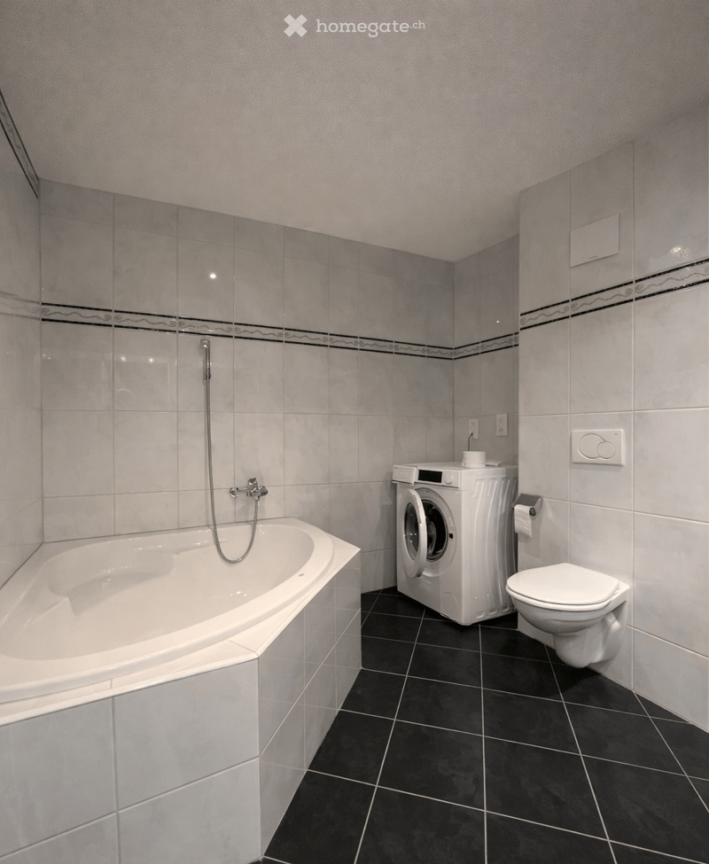 white bathtub, white washing machine, white toilet, white tiles, black tiles on the floor