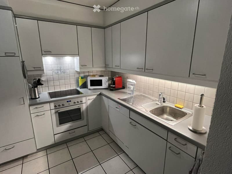 modern kitchen with white cabinets, tiled floor, stainless steel sink, dishwasher, microwave, coffee machine, refrigerator, oven, stove, and various kitchen utensils