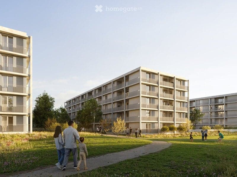 Modern apartment buildings with balconies, surrounded by a green park with walking paths