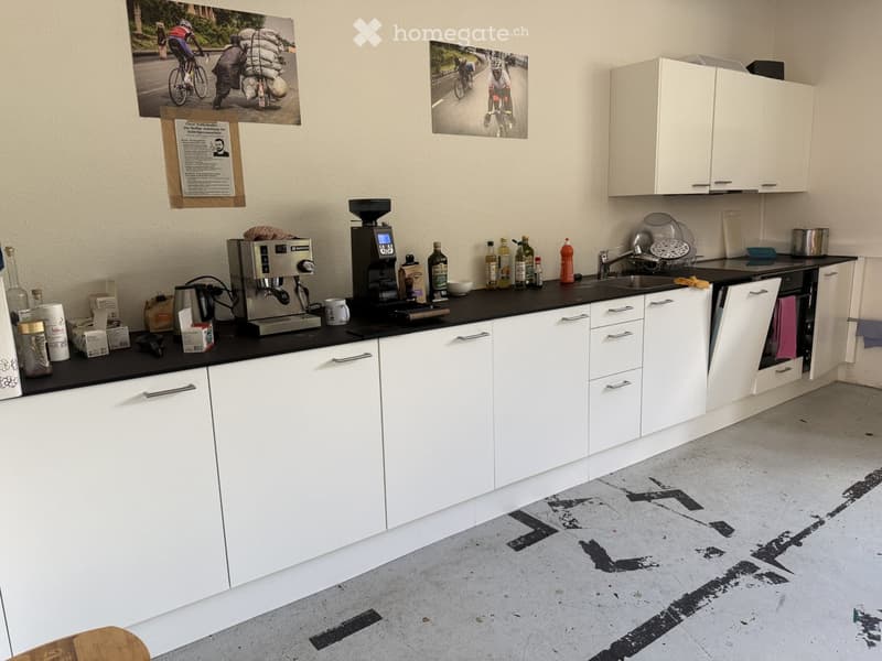 modern kitchen with white cabinets, black countertops, coffee machines, bottles, and a sink