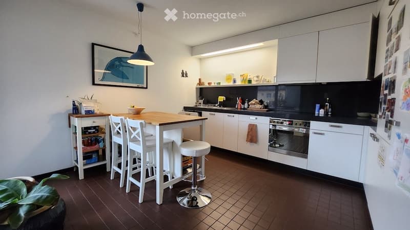 modern kitchen with white cabinets, wooden floor, island with bar stools, hanging lamp, refrigerator, oven, countertop, small table, potted plant