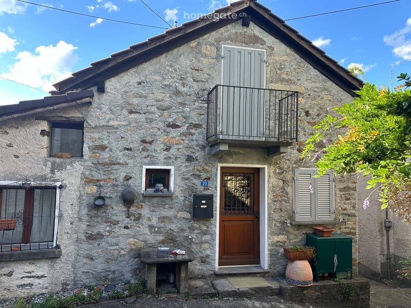Stone house, wooden door, balcony, windows with shutters, small garden, mailbox