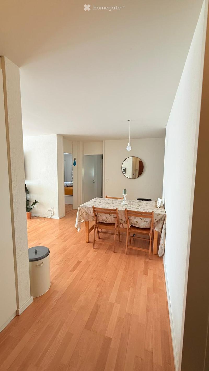Dining room with wooden floor, white walls, dining table, chairs, mirror, potted plant, power outlet, trash bin