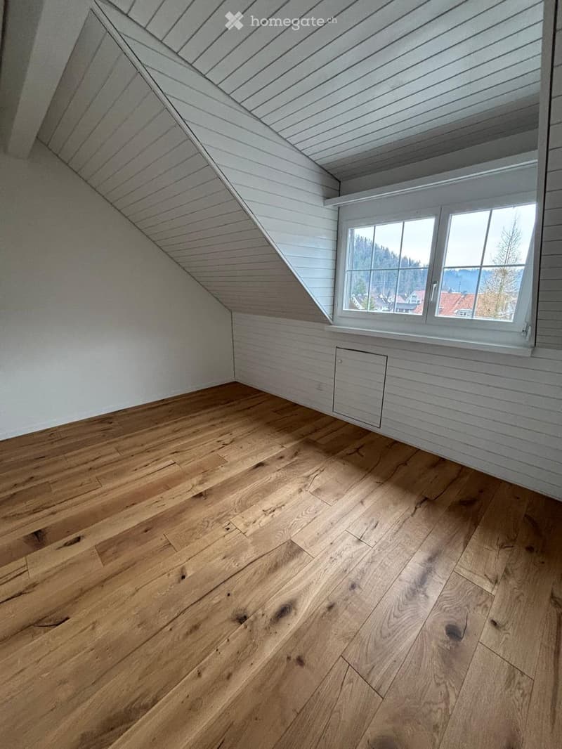 Empty room, wooden flooring, slanted ceiling, window with view