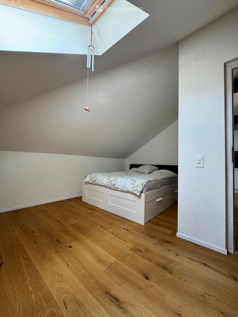 bedroom with bed, white walls, wooden floor, skylight