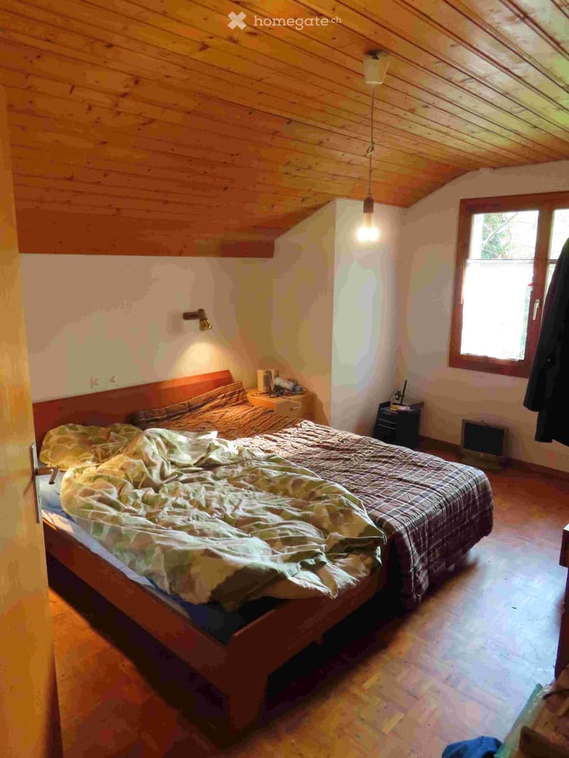 Bedroom with wooden ceiling, bed, nightstand, lamp, window, wooden floor