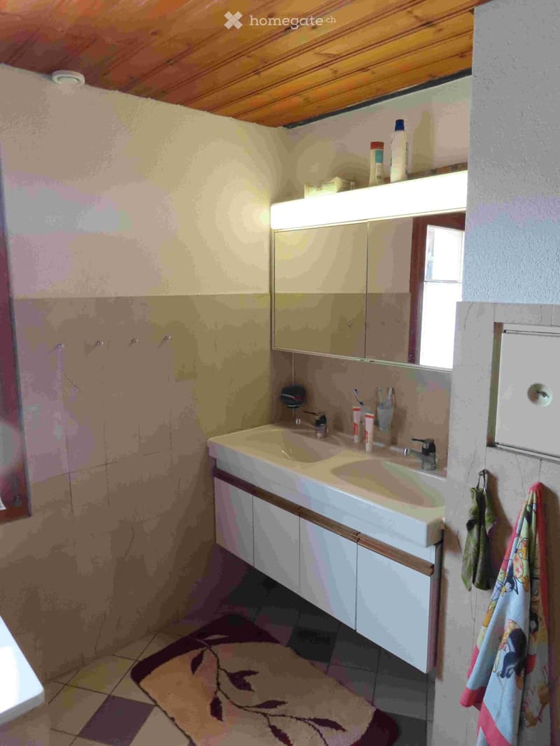 Bathroom with double sink, mirror, towel rack, and a rug on the floor.