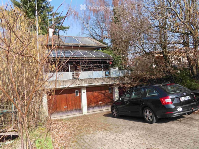 2 story house, solar panels on roof, wooden garage, car parked in front