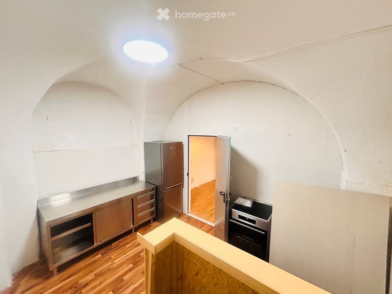 empty kitchen with steel appliances, wooden floors, arched wall design