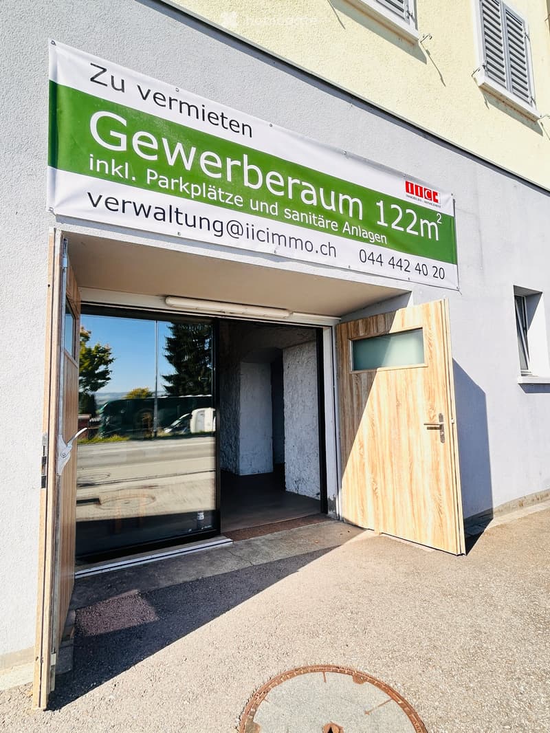 Entrance to the commercial spaces with parking sign, wooden doors, entrance light, reflecting the exterior and open space