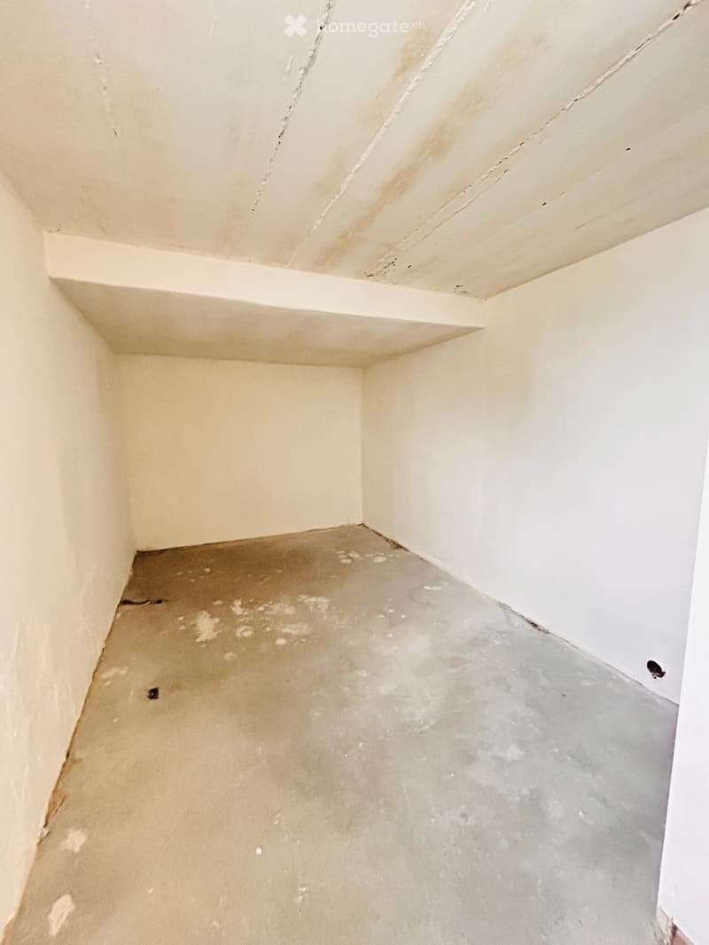 Empty room with white walls and concrete floor, no furniture or decorations, with a small hole in the wall.