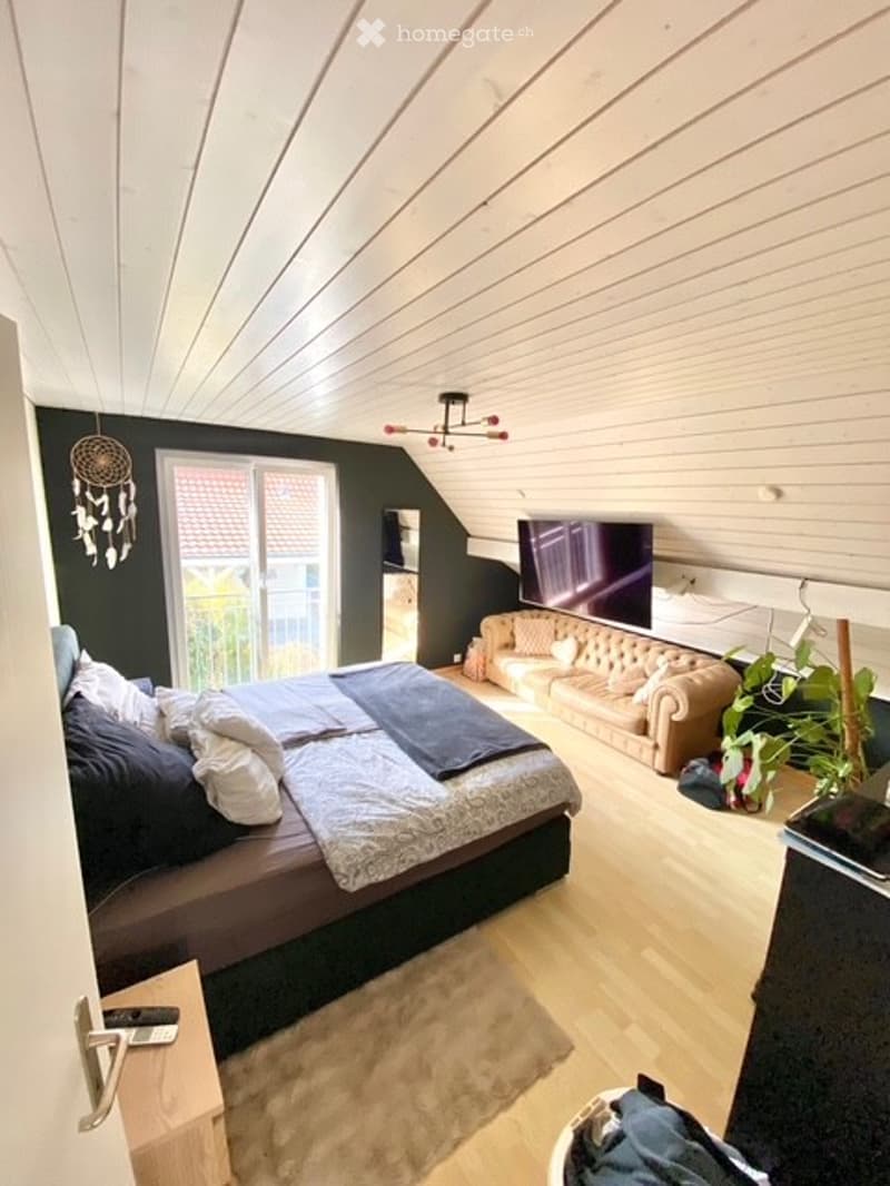 Bedroom with bed, couch, TV, rug, wooden floor, white ceiling, balcony, plants, remote control