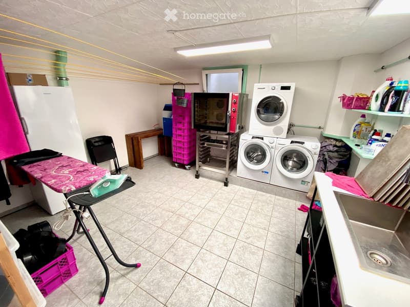 Laundry room with washing machines, ironing board, refrigerator, shelves, and storage boxes