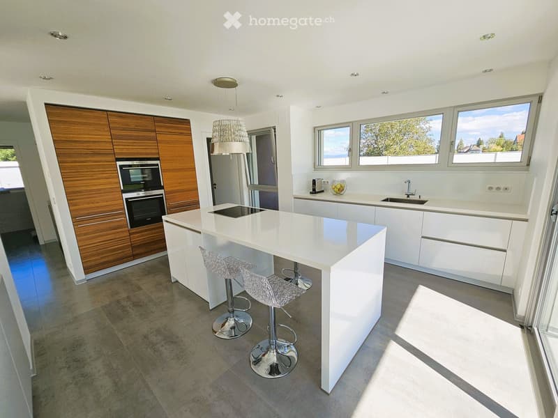 modern kitchen with white countertops, wooden cabinets, stainless steel appliances, large windows, and a view of the outside