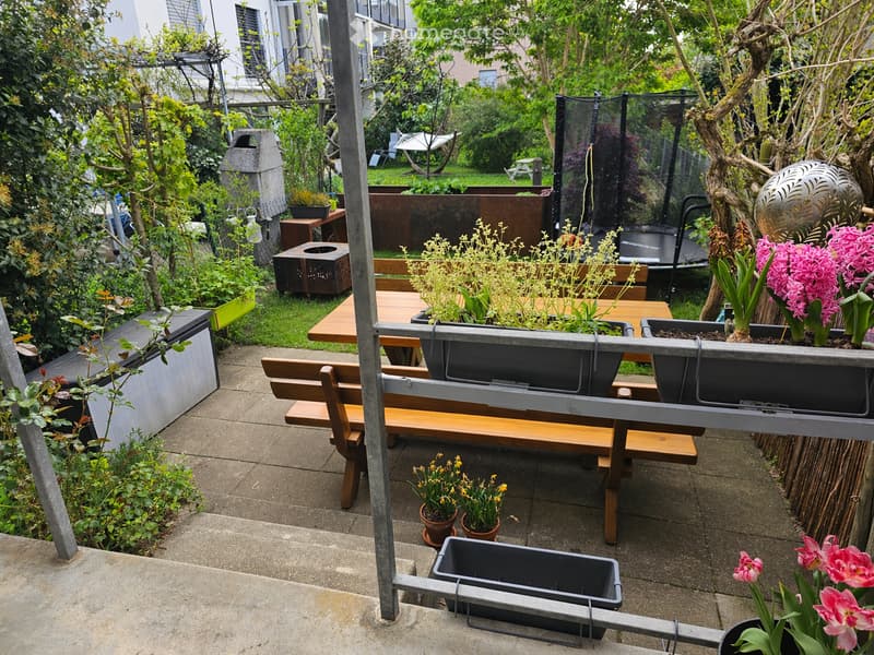 Wooden bench, wooden table, potted plants, flowers, trampoline, metal fence, metal railing, concrete floor, metal poles