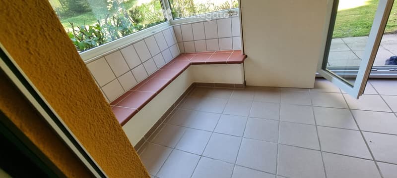 Balcony with tiled seating area, large windows, and access to outdoor space.