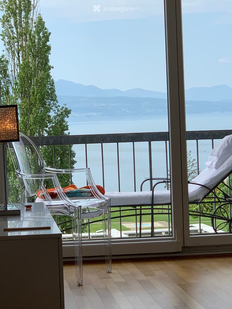 large balcony, two transparent chairs, a lamp, view of the sea and the mountain