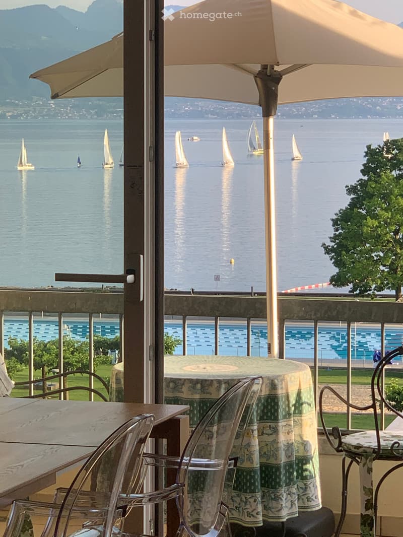glass door leading to a balcony, pool in the background, lake view, table and chairs
