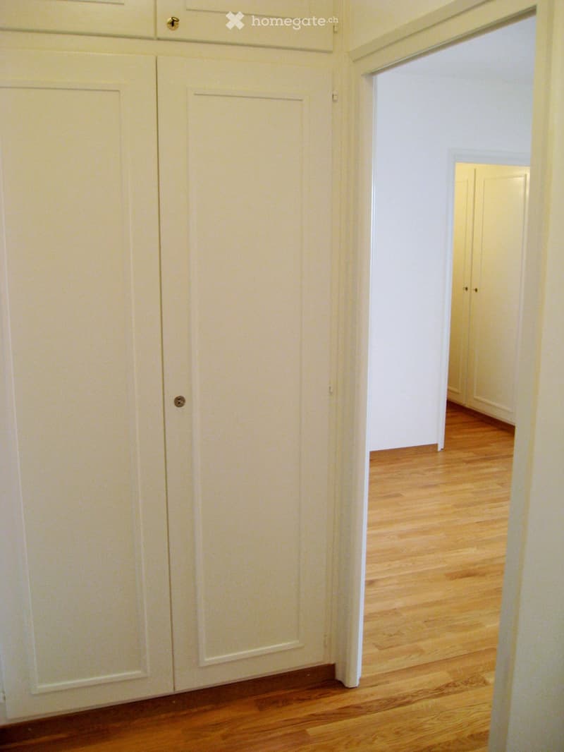 Empty room with two doors, wooden floor, white painted walls