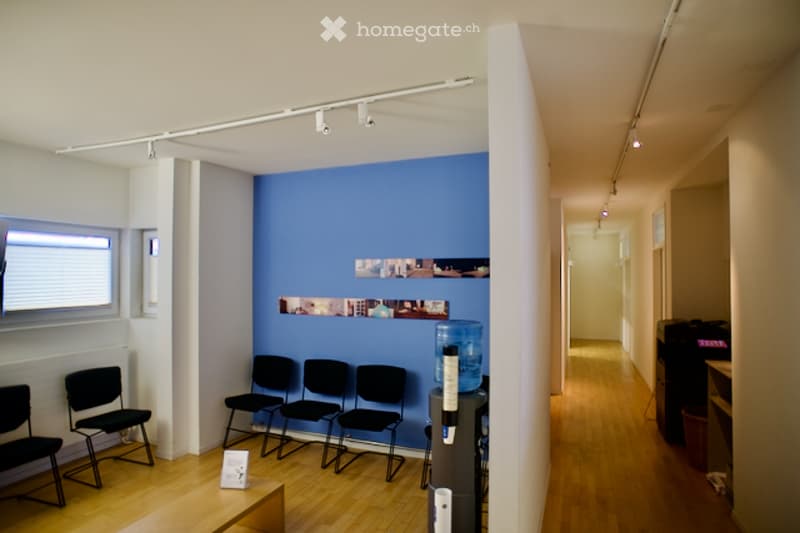 Blue wall, wooden floor, chairs, water dispenser, radiator, window