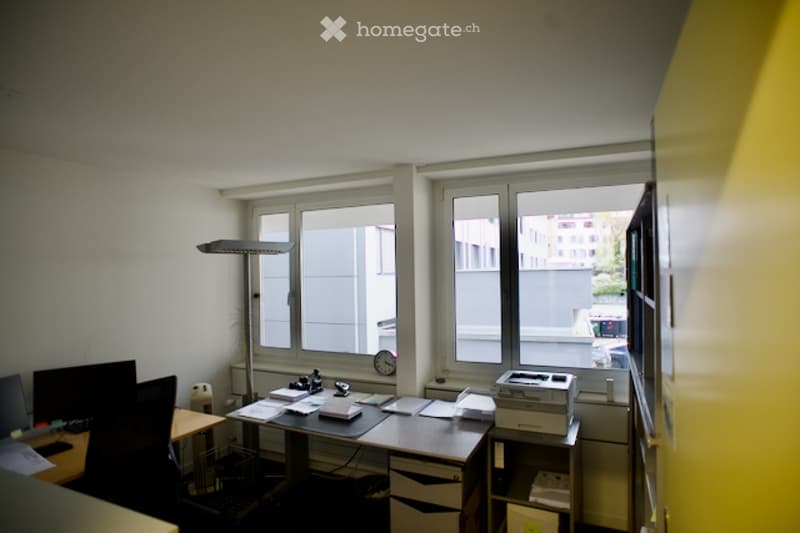 Office room with desk, computer, printer, chair, lamp, clock, and large windows