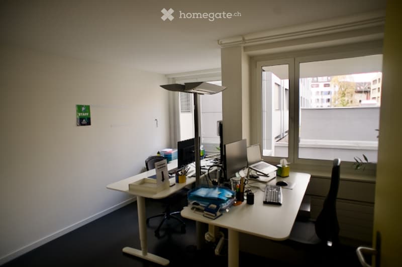 Office room with two desks, chairs, computer monitors, keyboards, and a lamp
