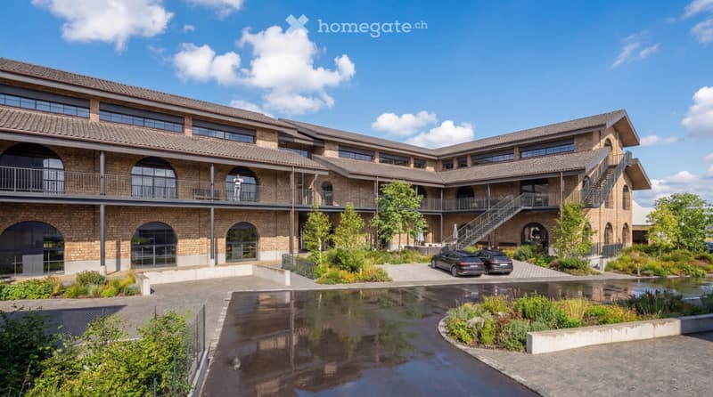 3 story building, brick facade, large windows, balconies, parking area, garden