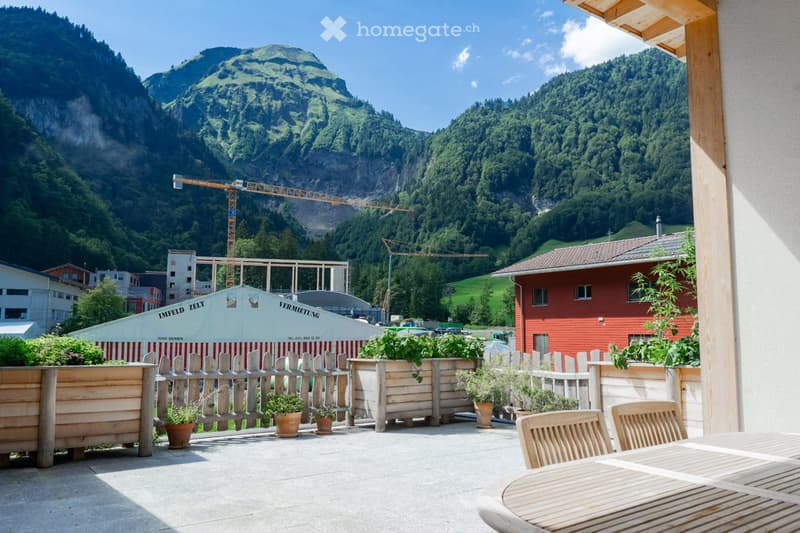patio with wooden table and chairs, white tents in the background, mountain landscape