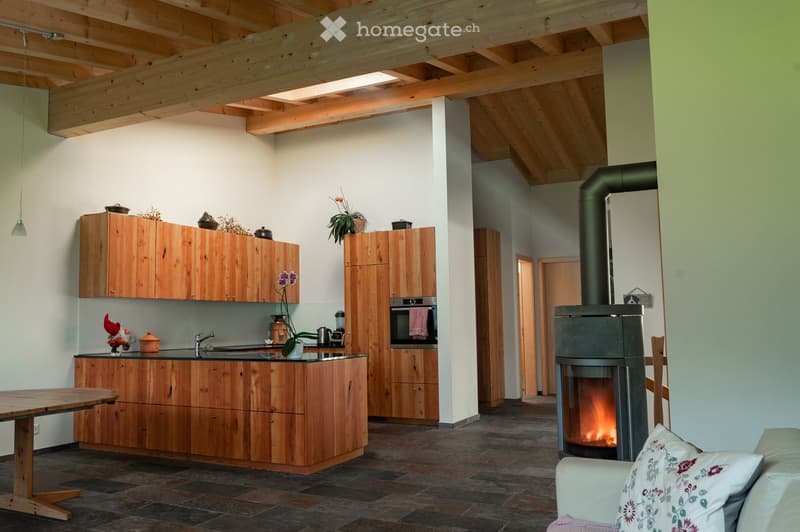 open kitchen with dining table, modern fireplace, wooden cabinets, white and green walls, hanging light, modern furniture