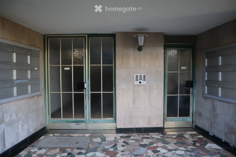 Double glass doors, tiled floor, wall mounted light, mailboxes, intercom system
