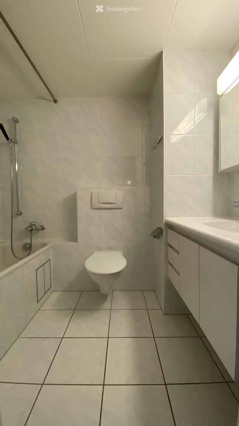 Bathroom with white tiles, bathtub, toilet, sink, mirror, shower head