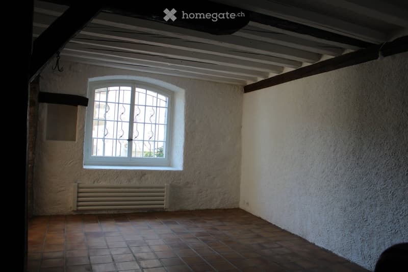 empty room, white walls, brown tiles, window with metal grill, white radiator