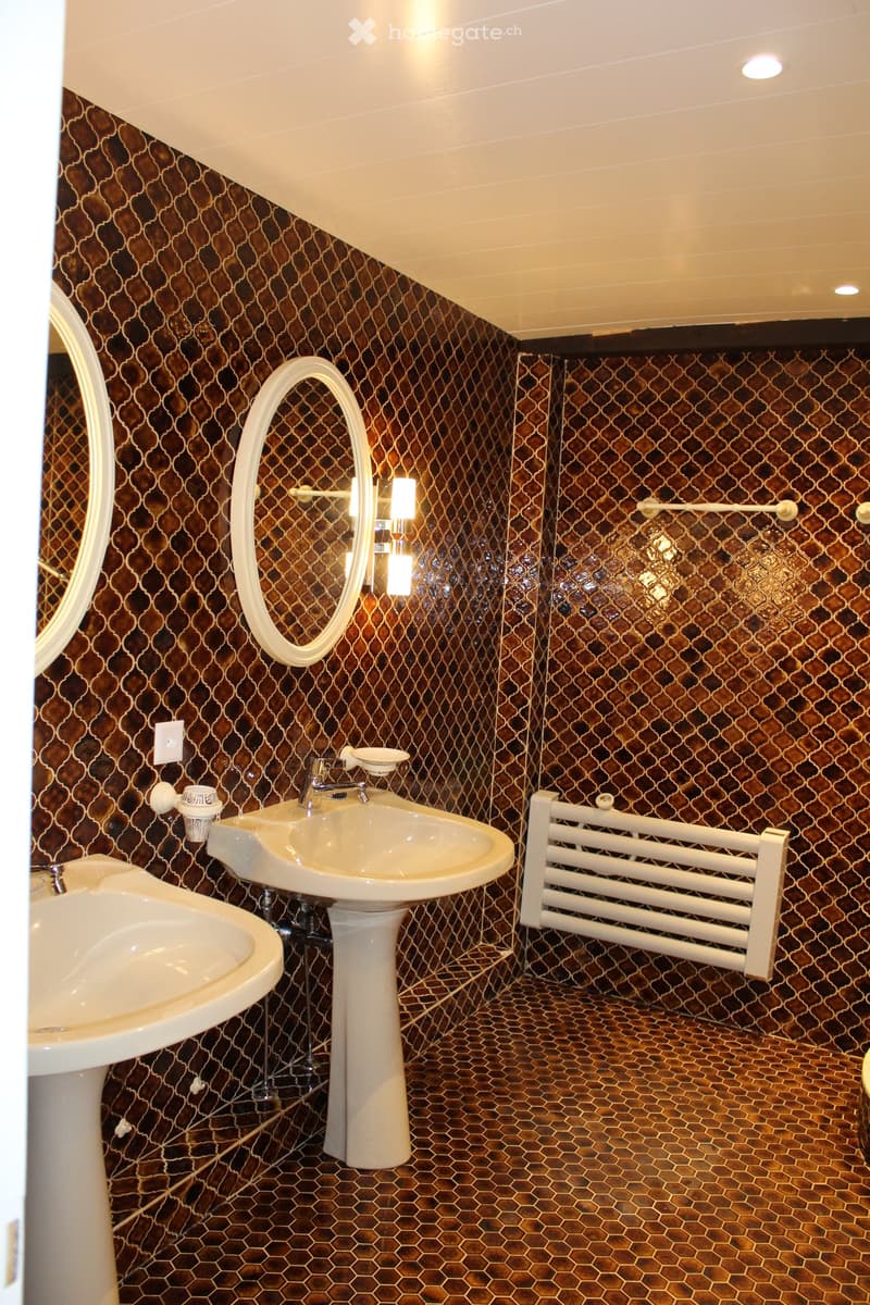 Bathroom with two sinks, two mirrors, and tiled walls and floor.