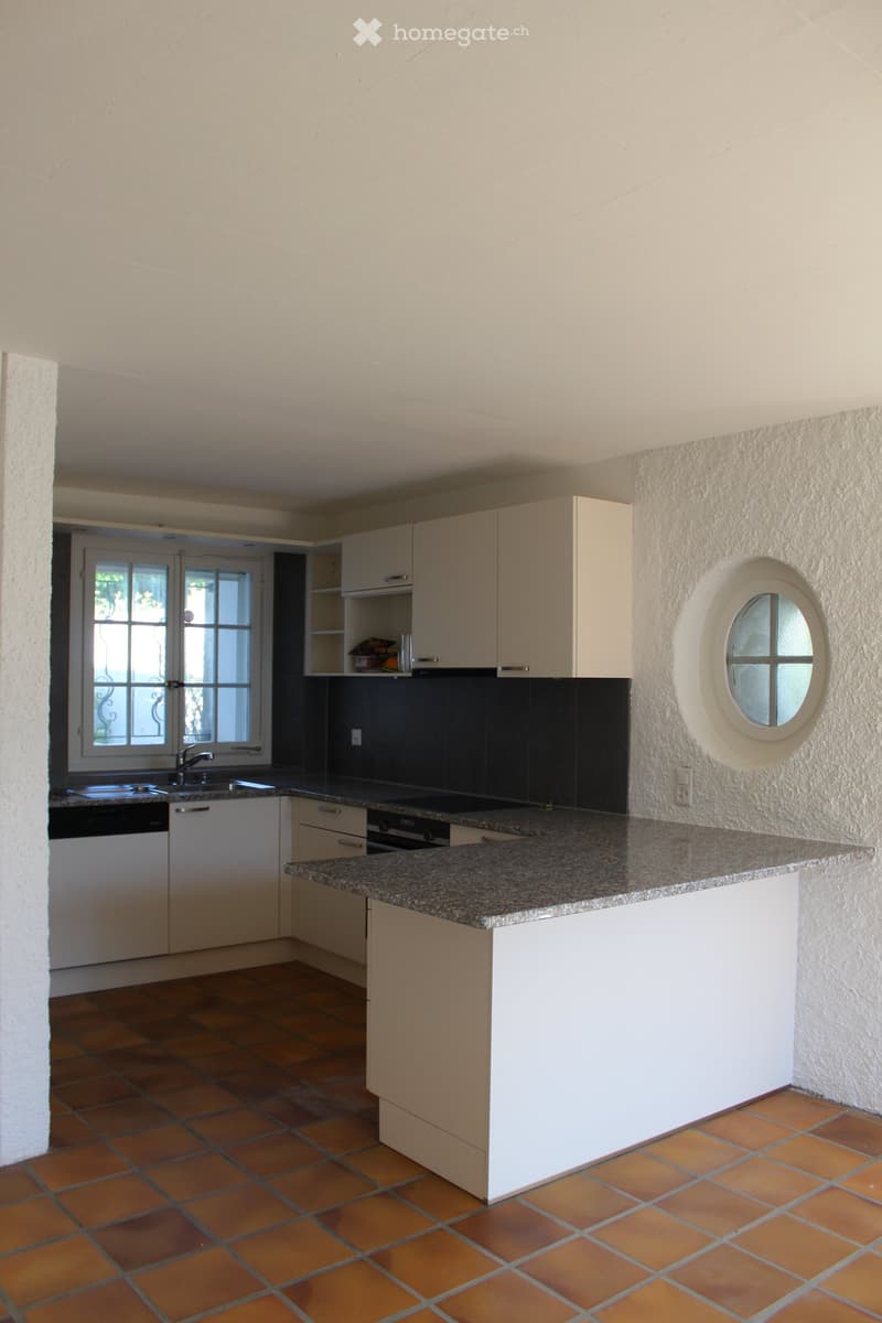 modern kitchen with white cabinets, granite countertop, round window, tiled floor