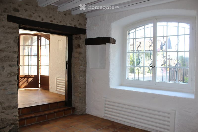 Stone wall, wooden door, tiled floor, white wall, window with metal grills