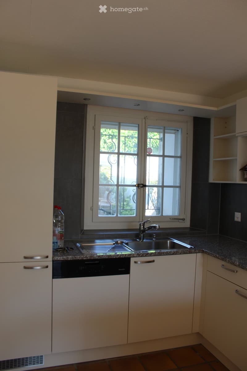 modern kitchen with white cabinets, granite countertops, stainless steel sink, dishwasher, window with grills