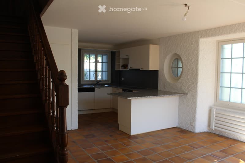 kitchen with island, white cabinets, tiled floor, window, stairs