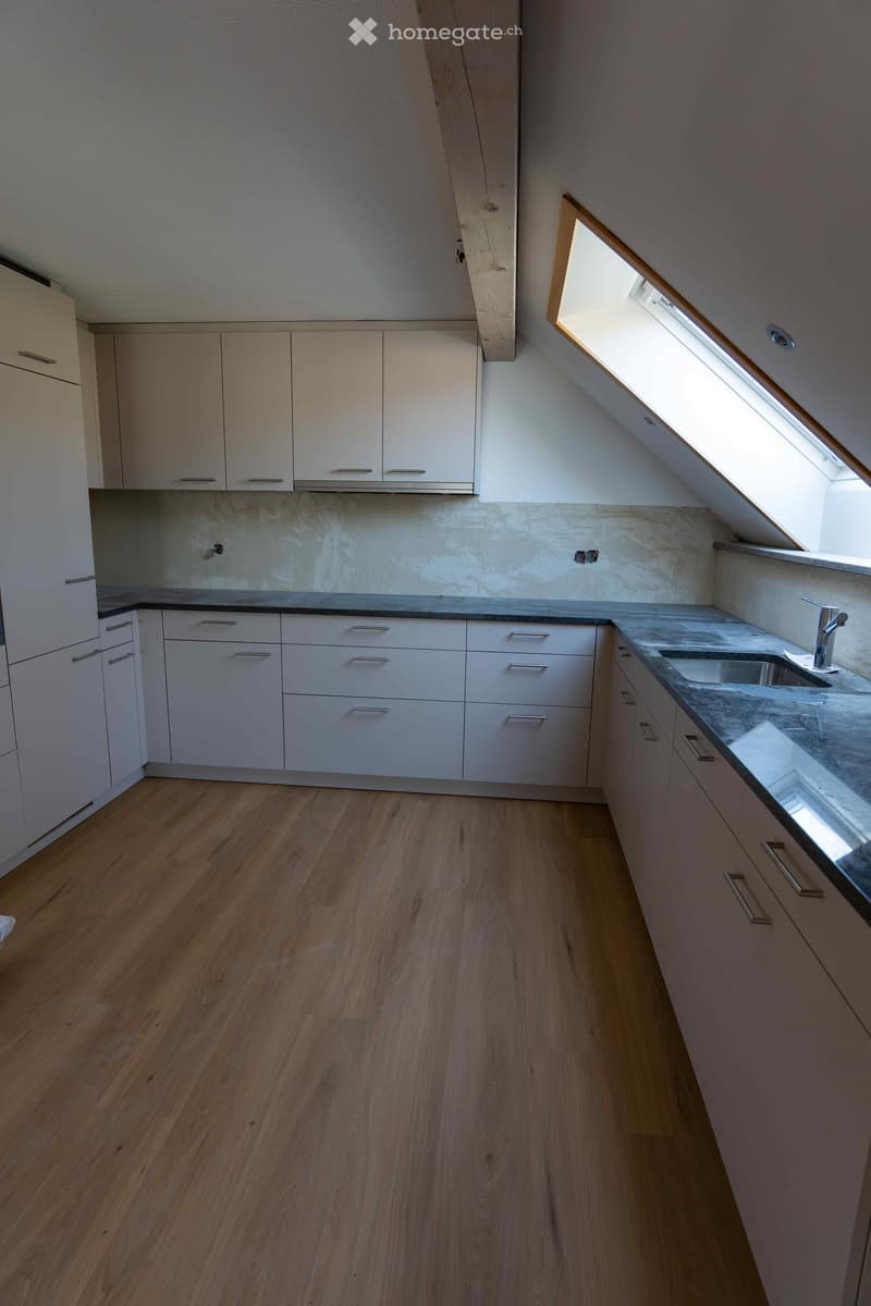 kitchen with white cupboards, wooden floor, grey granite countertops, sink, loft window