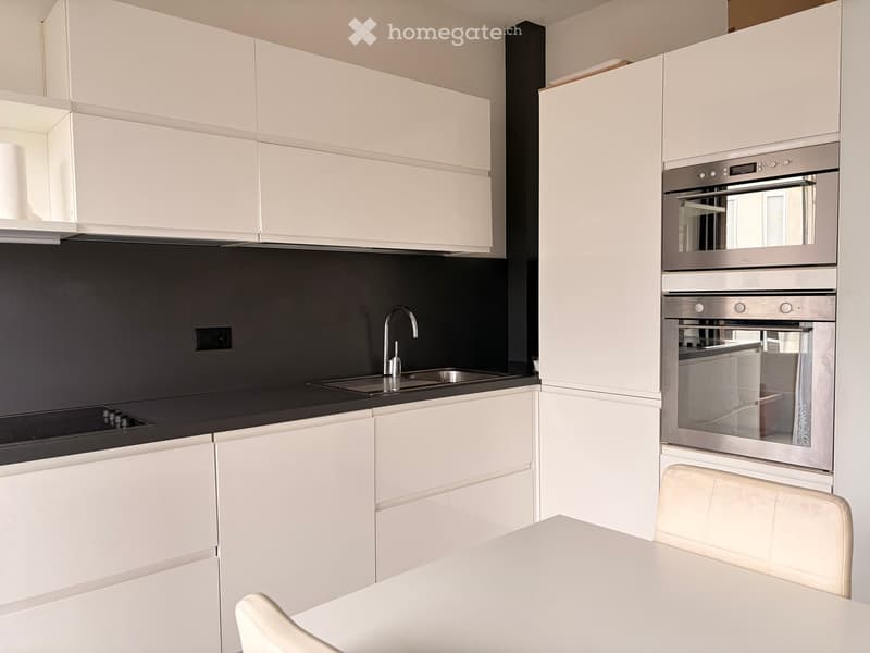modern kitchen with white cabinets, black countertops, stainless steel sink, oven, dishwasher, faucet